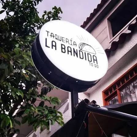 Aviso circular luminoso de doble cara montado en bandera sobre la fachada de un restaurante, encendido de noche.