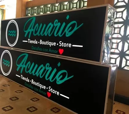 Dos avisos rectangulares con marco metálico y fondo negro, terminados y apoyados en el suelo antes de la instalación.
