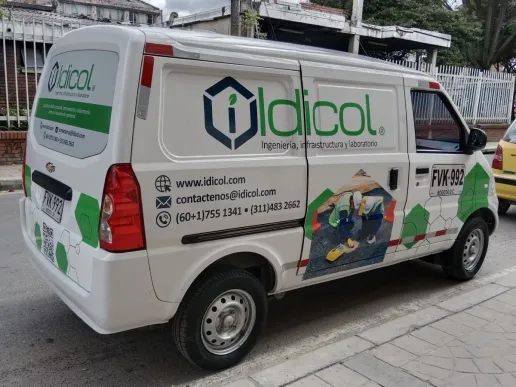 Furgoneta blanca con rotulación completa en vinilo impreso: logotipo, datos de contacto y una franja verde que recorre el lateral.